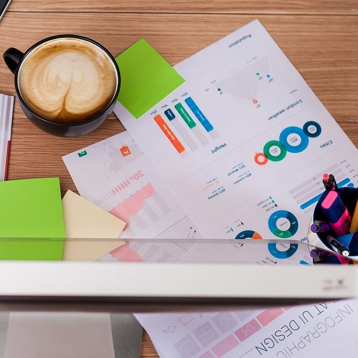 Kaffee, Notizen und Diagramme auf einem Tisch mit bunten Haftnotizen.