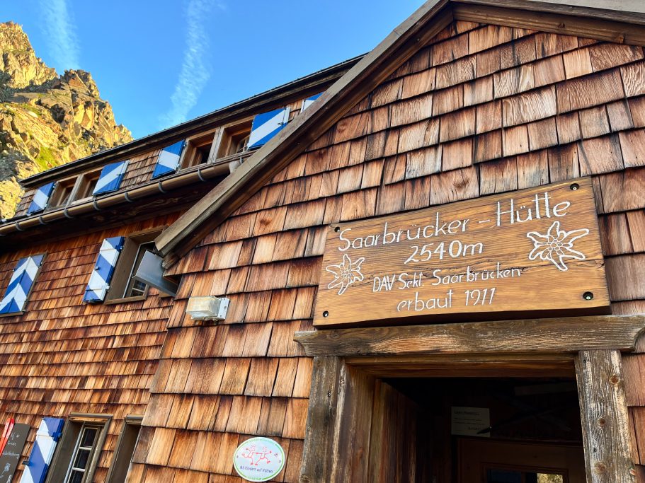 Saarbrücker Hütte Fachwerkgebäude mit Holzbretterfassade und einem Schild mit dem Namen des Lokals.