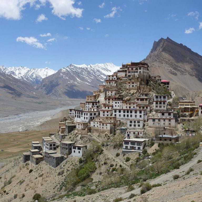 Buddhist-Kloster auf einem Hügel, umgeben von Bergen und einem Fluss im Tal.