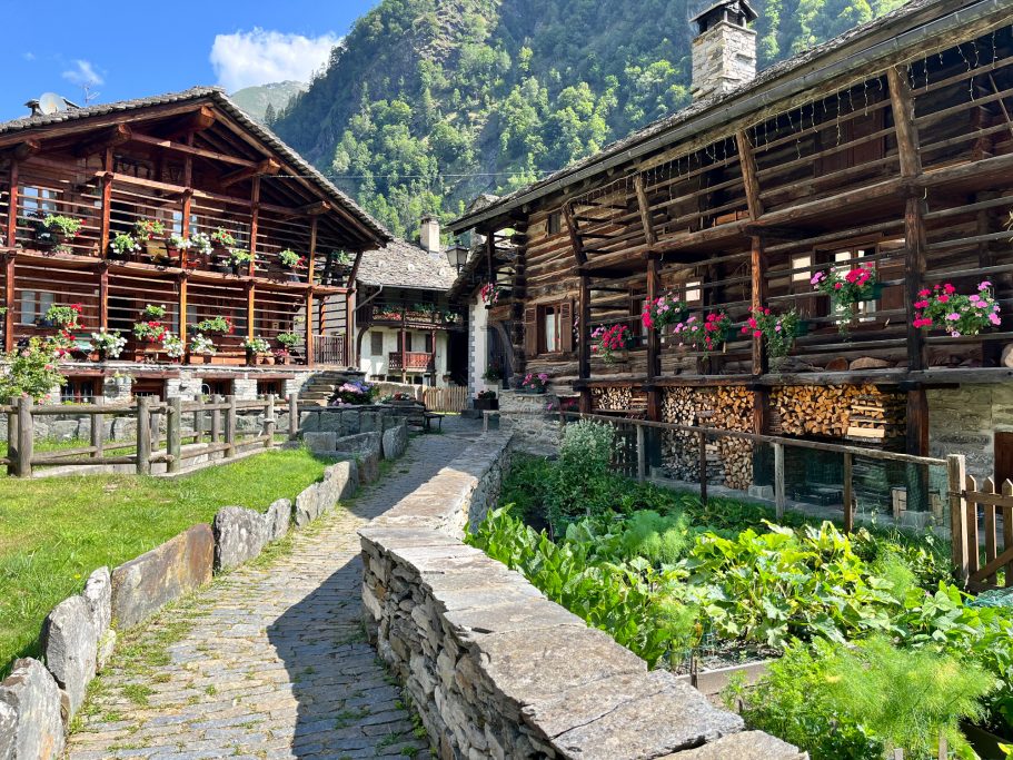 Alagna Traditionelle Holzhäuser in einer malerischen Berglandschaft mit blühenden Fenstern.