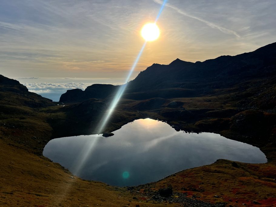 Monviso Sonnenaufgang über einem stillen Bergsee mit dramatischer Landschaft im Hintergrund.