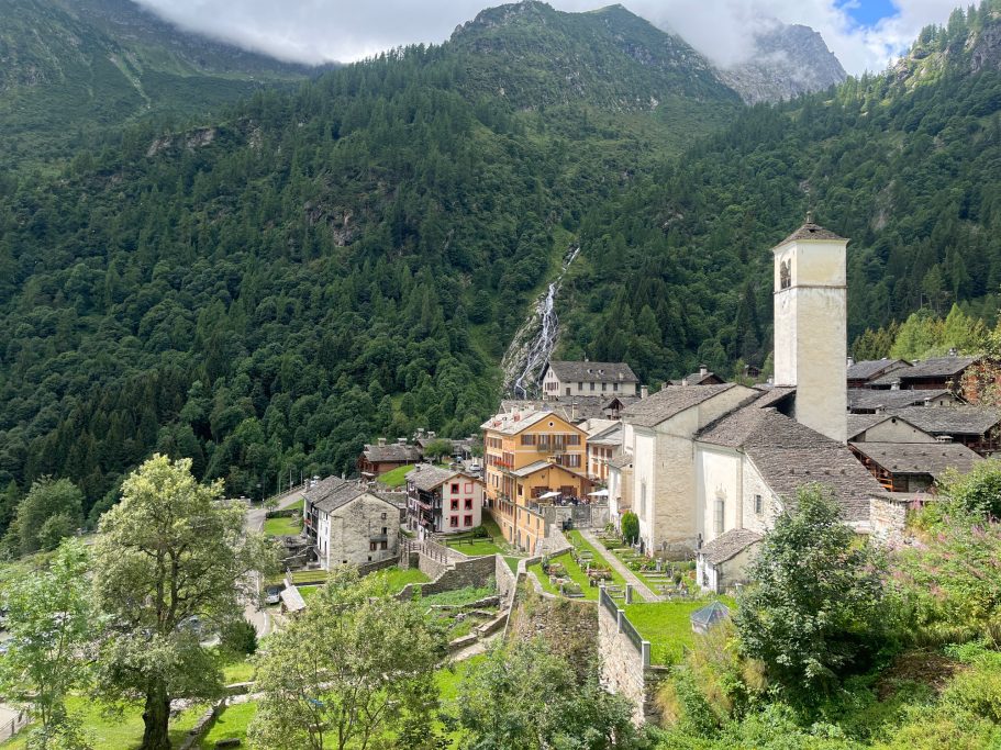 Blick auf ein malerisches Dorf umgeben von Bergen und üppiger Natur.